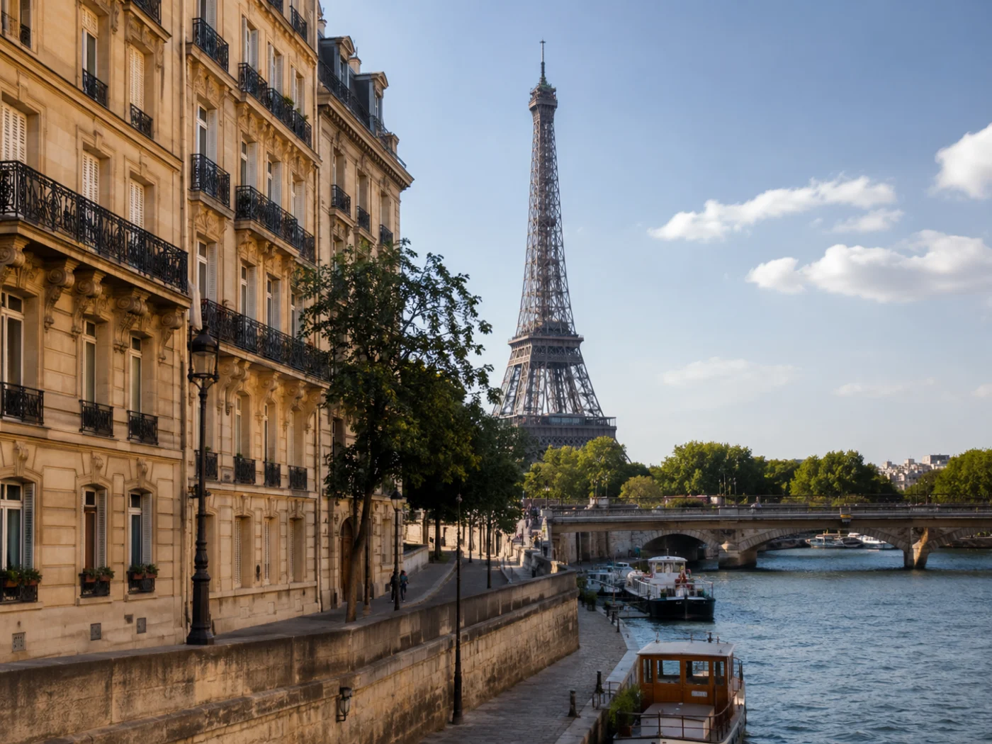 De Eiffeltoren gezien vanaf de Seine in Parijs, met haussmanngevels en rondvaartboten