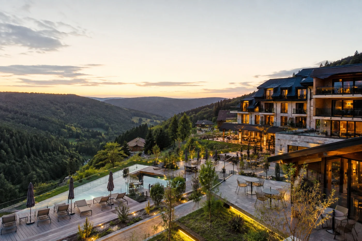 Wellnesshotel met panoramazwembad en terrassen op een heuvel, met avondzon over de beboste heuvels van het Zwarte Woud
