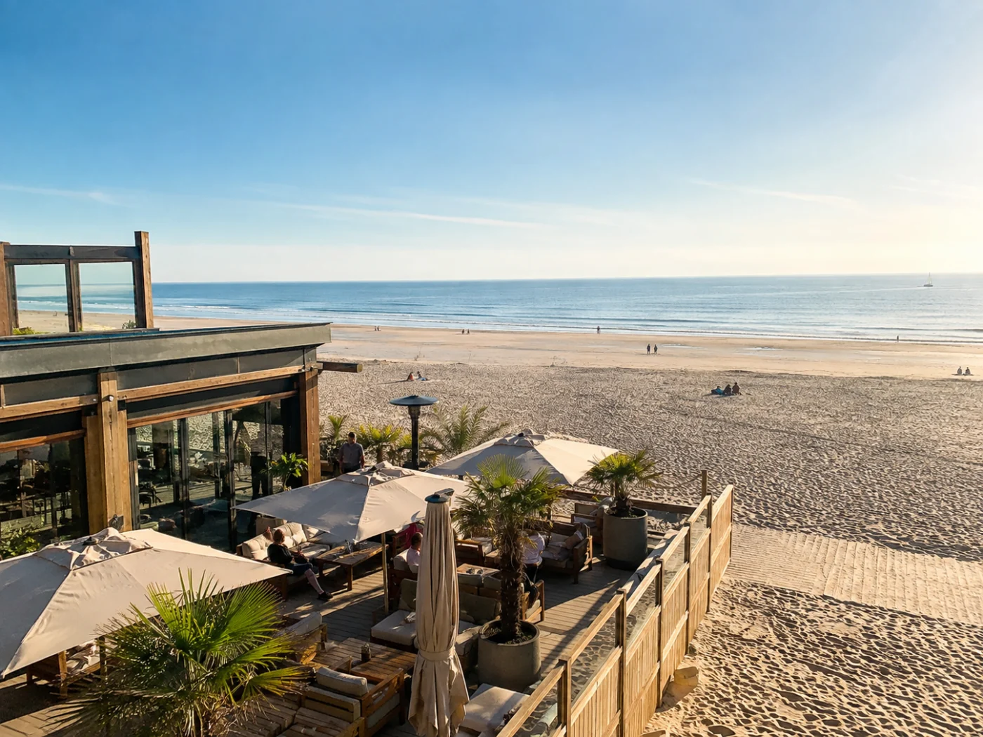 Strandpaviljoen met loungeterras en parasols aan een breed Nederlands zandstrand aan de Noordzee