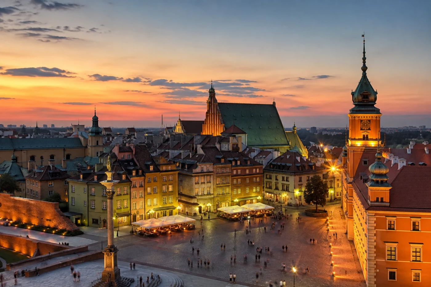 De oude stad van Warschau bij zonsondergang, met het Koninklijk Kasteel, de Sigismundzuil en verlichte terrassen op het Kasteelplein